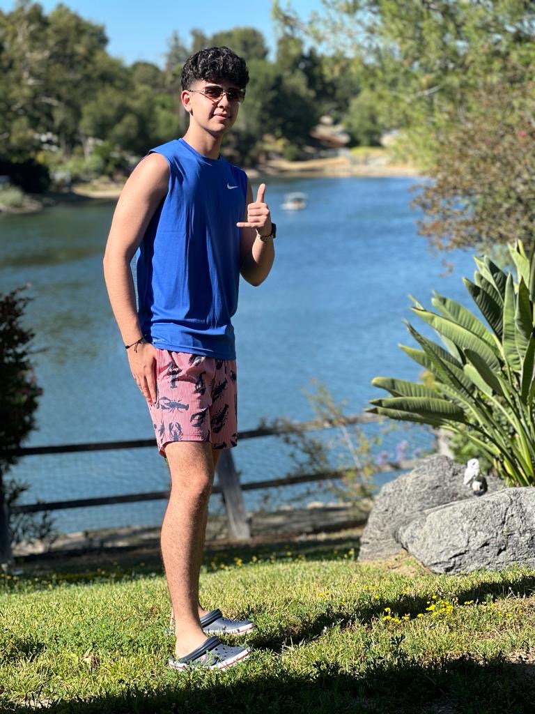 Image of a young man posing in front of a lake during the day